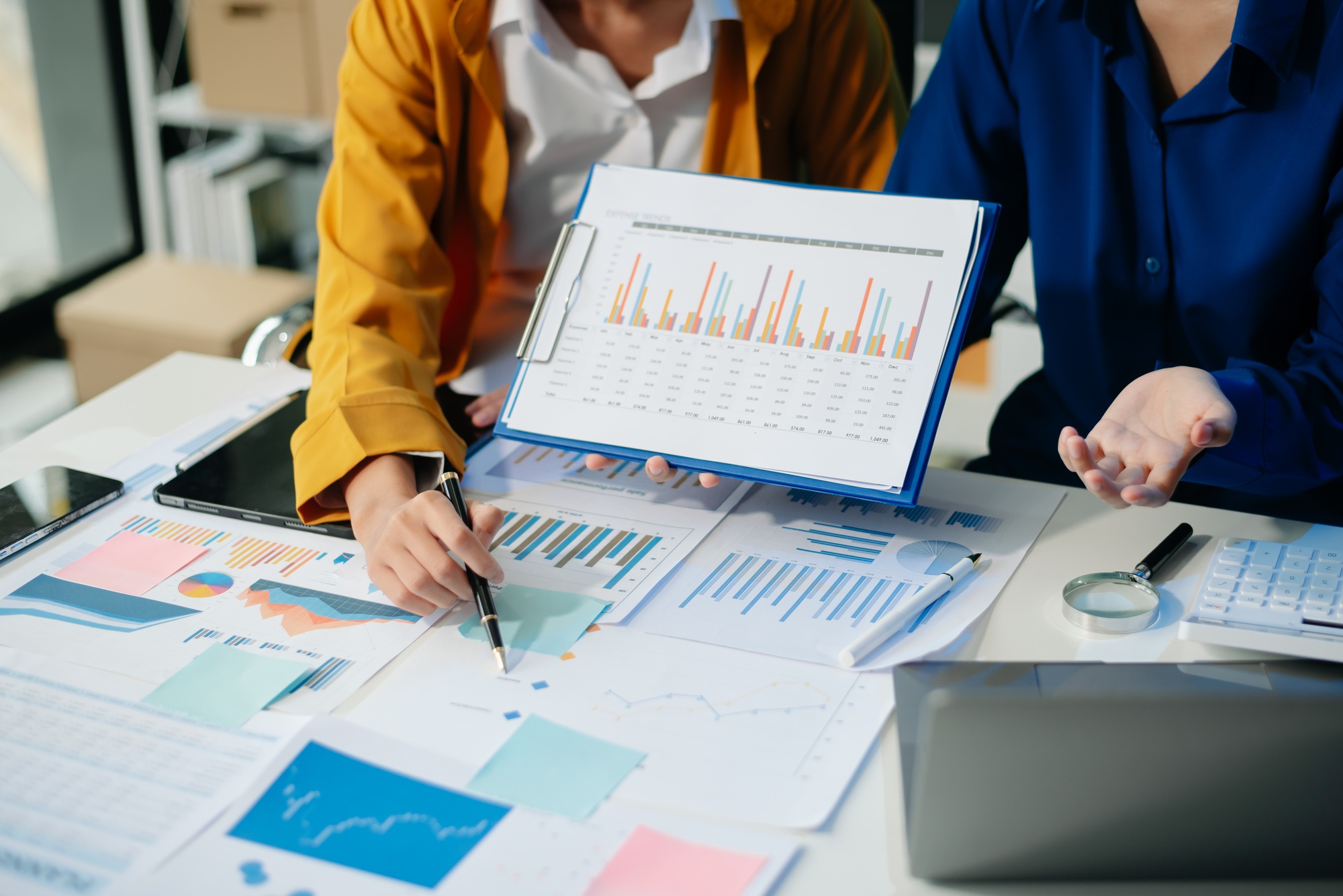 Business documents on office table with smart phone and calculator digital tablet and graph